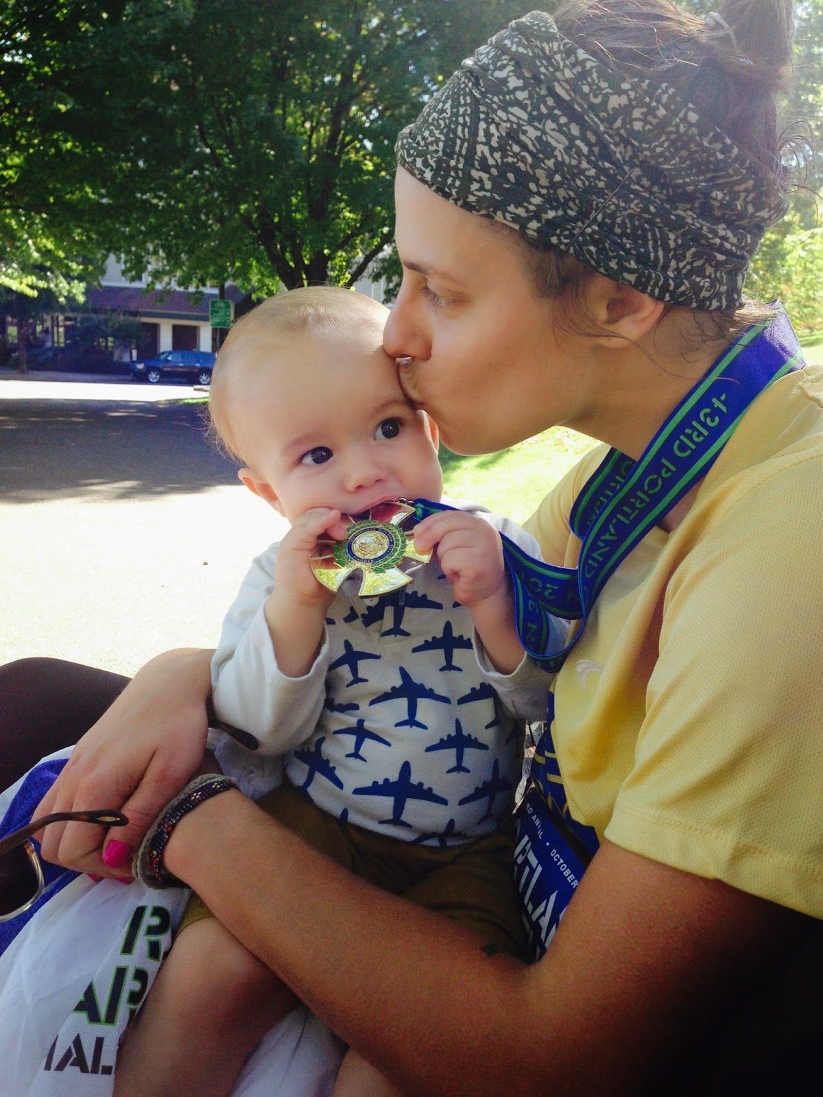 Woman kissing baby with a portland marathon medal in mouth