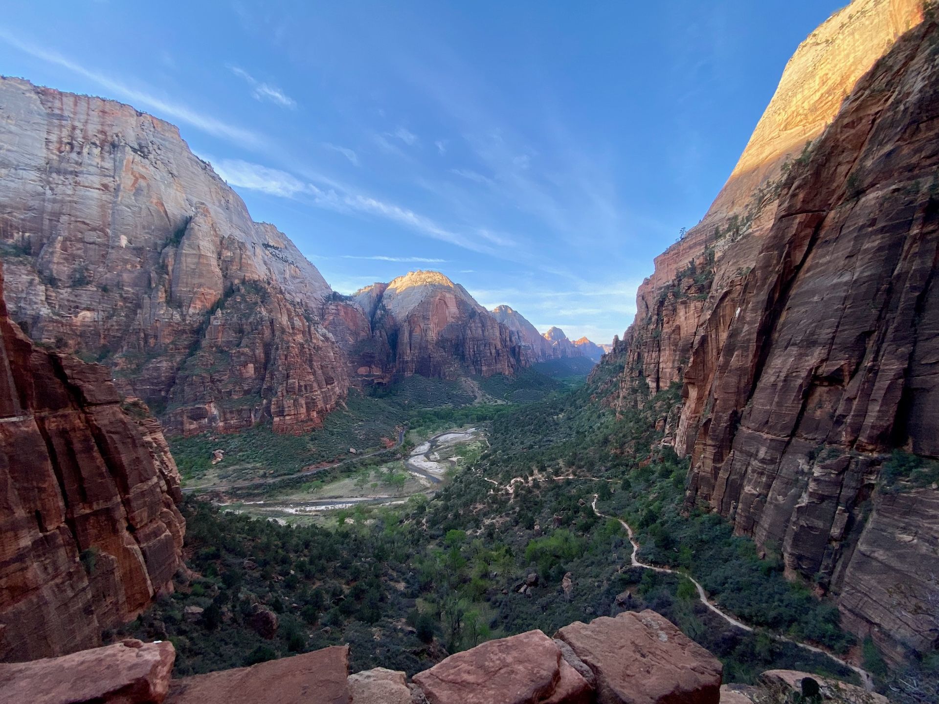 hiking path to angels landing, looking down on a green valley with towering red cliffs