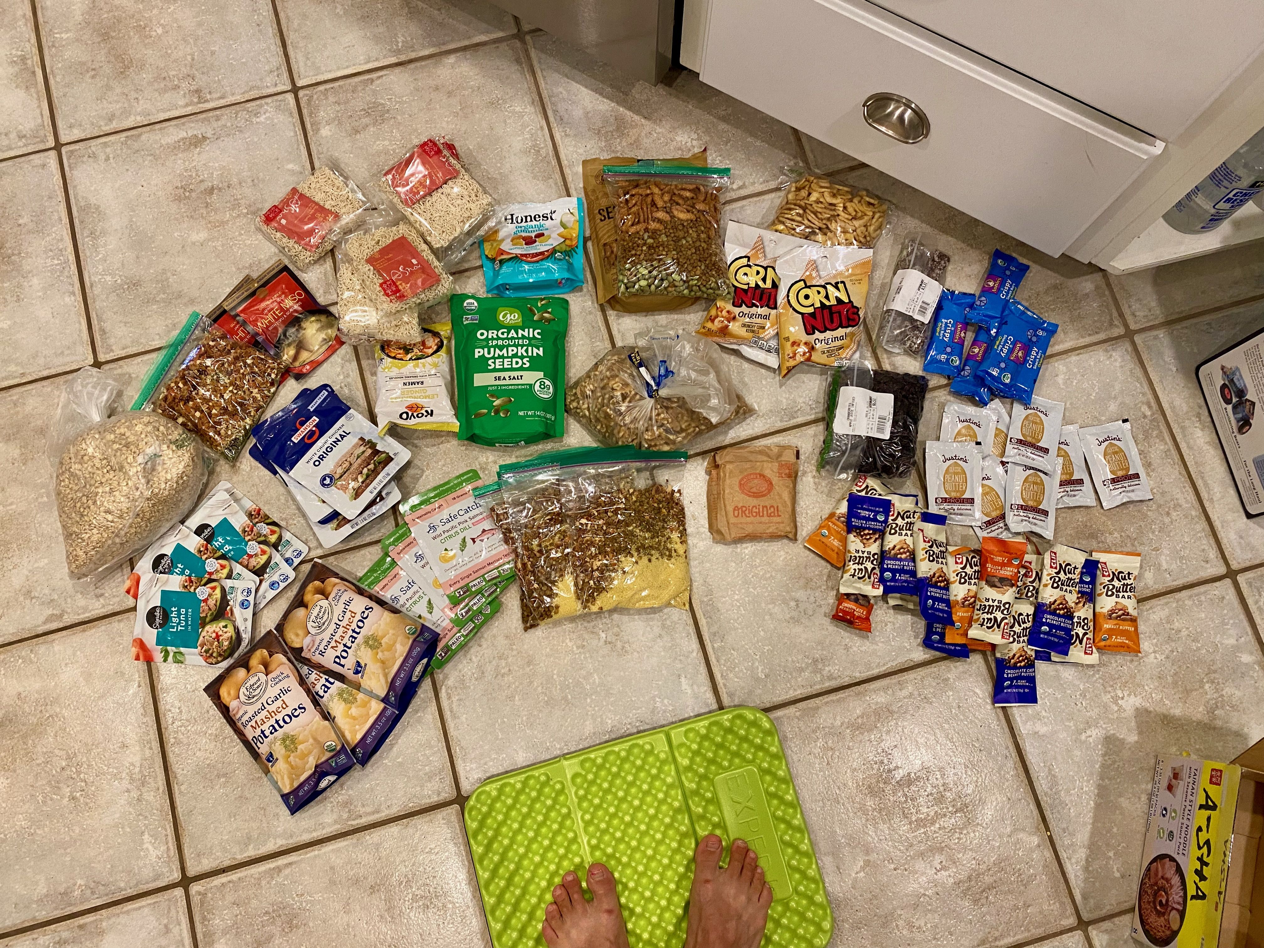 A bunch of backpacking food organized on the floor